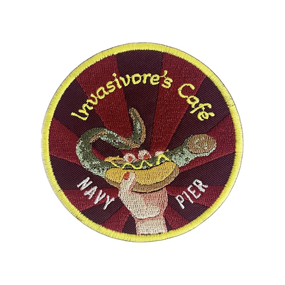 Round patch illustration featuring a invasive species within a hotdog bun with mustard, labeled “Invasive’s Café – Navy Pier.”